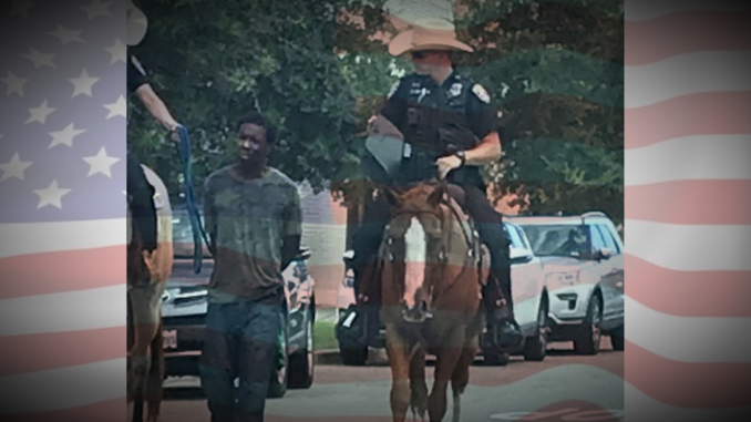 Američki policajac na konju vodi privedenog Afroamerikanca na povocu